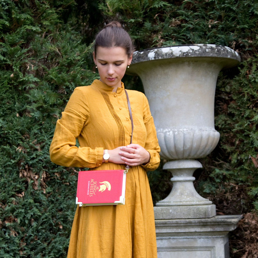 The Song of Achilles Red Handbag by Madeline Miller featuring Gold Trojan Helmet design, by Well Read Co. - Model in Yellow Dress
