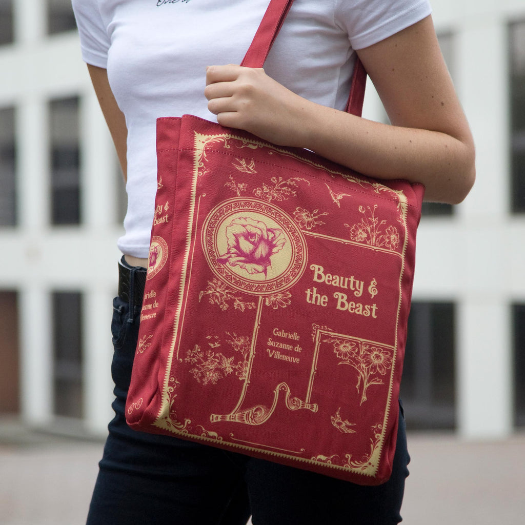 Beauty and the Beast Red Tote Bag by Gabrielle-Suzanne de Villeneuve featuring Gold Flowers and Swallows design, by Well Read Co. - Model Standing