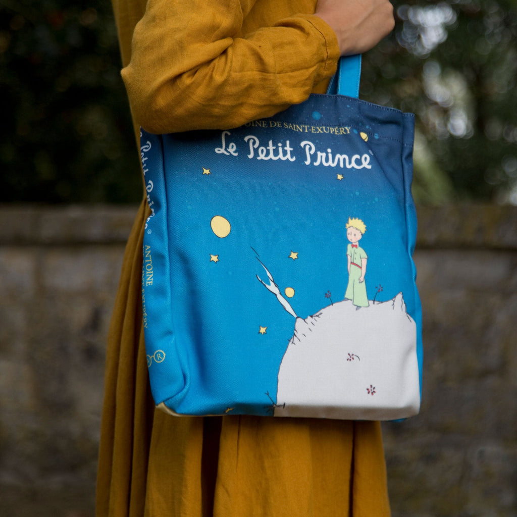 The Little Prince Blue Tote Bag by Antoine de Saint-Exupéry featuring Little Prince on his Home Planet design, by Well Read Co. - Model with bag