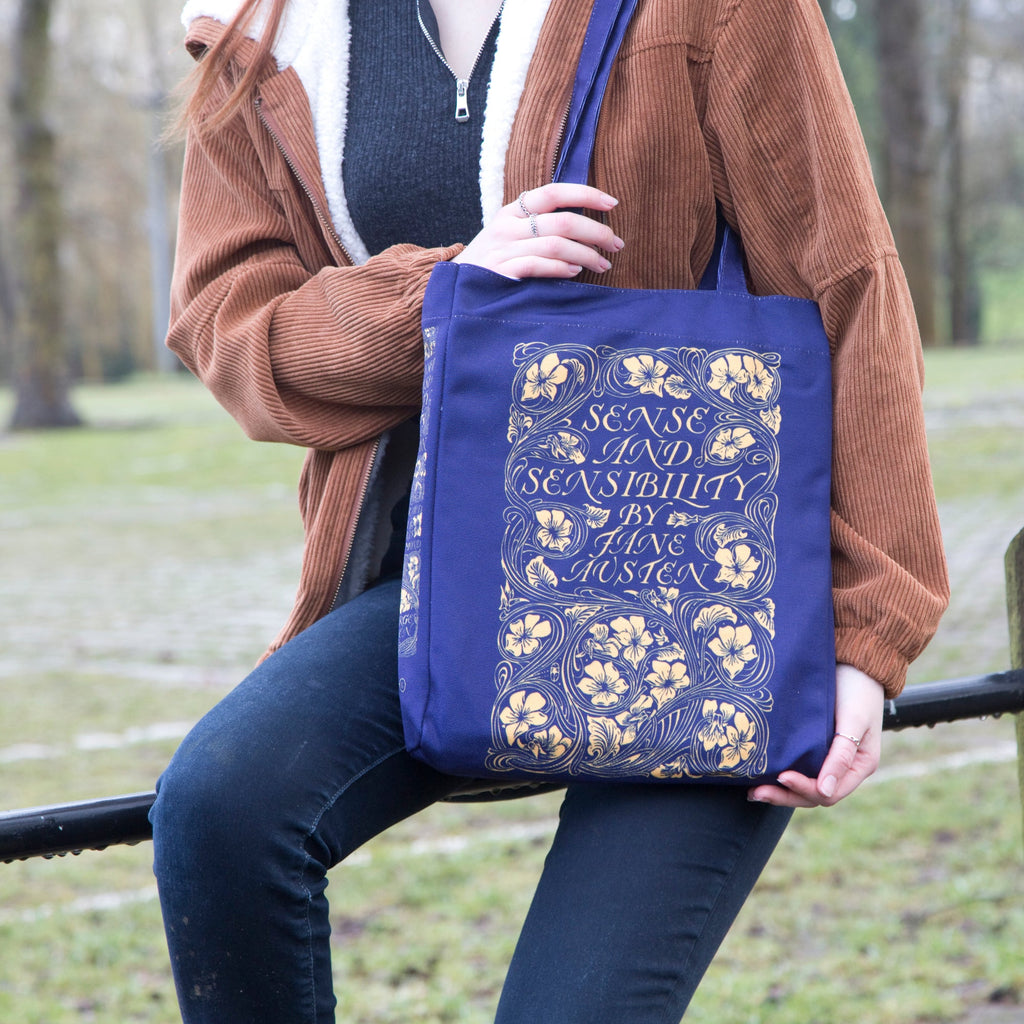 Sense and Sensibility Blue Tote Bag by Jane Austen featuring Gold Flower design, by Well Read Co. - Model Sitting